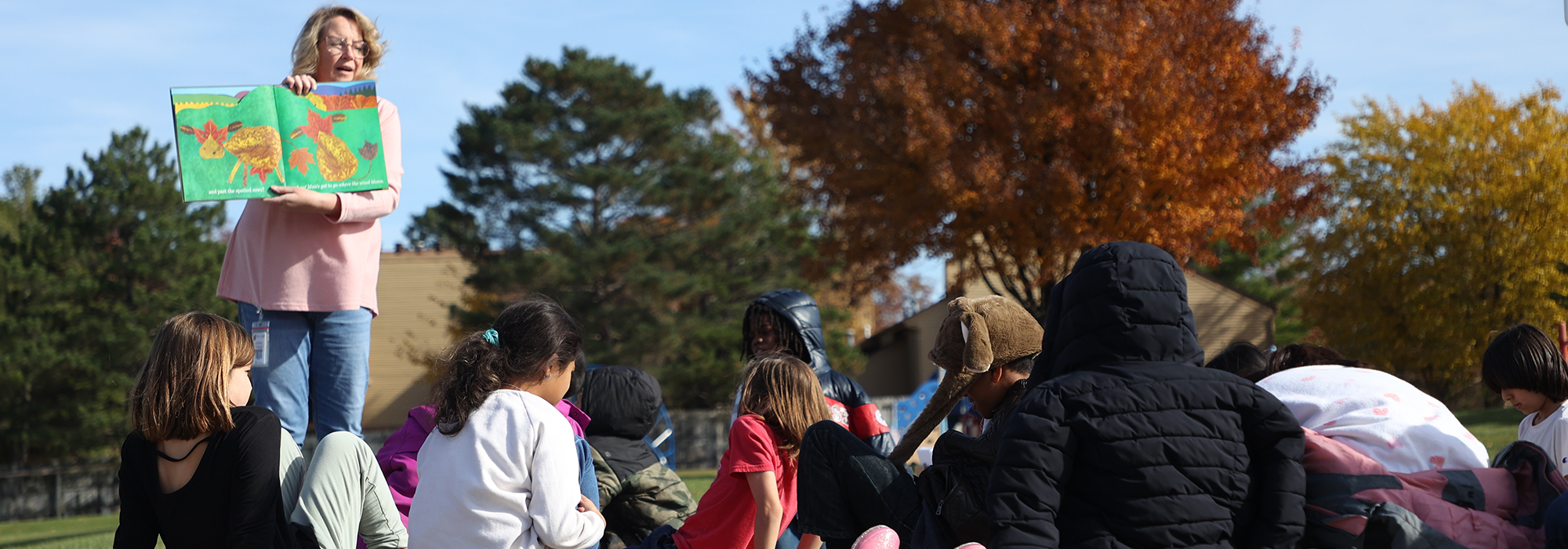 Teachers reads to students outside